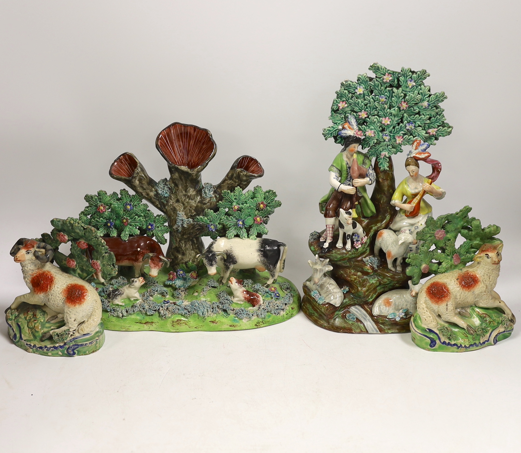 Four 19th century Staffordshire figurative groups; two musicians with sheep, etc. cows with calves group, and a pair of sheep and ram stamped ‘salt’, tallest 27cm